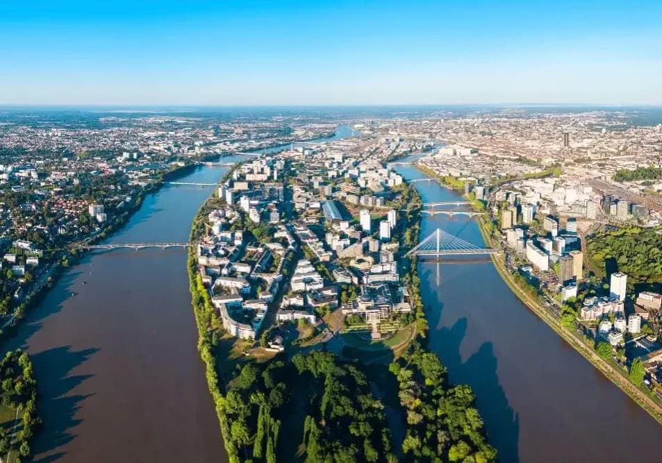 Panorama aérien de l'Île de Nantes entourée par la Loire, zone stratégique pour la location de bureaux avec ponts et espaces verts.