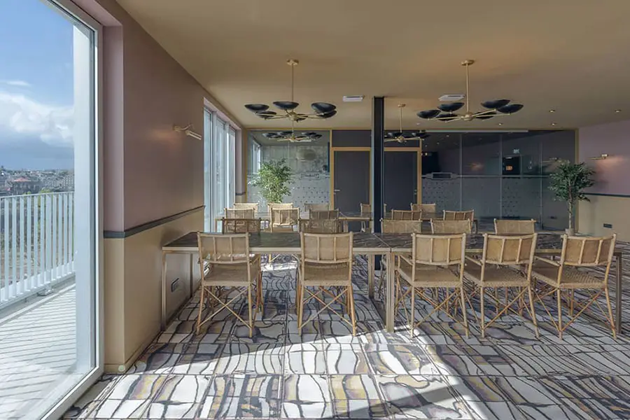 Un espace de coworking à Nantes avec un design intérieur moderne, équipé de chaises hautes en osier et de tables assorties, situé près de grandes baies vitrées offrant une abondance de lumière naturelle et une vue imprenable sur la ville.
