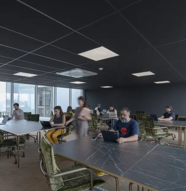 Vue d’un espace de coworking moderne à Nantes, avec des coworkers concentrés autour de grandes tables.