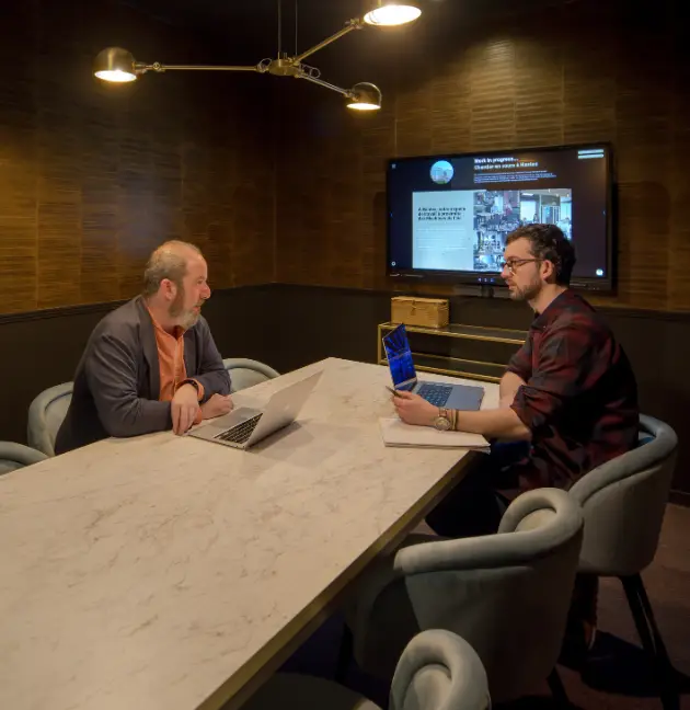 Deux coworkers en discussion dans une salle de réunion équipée et élégante à Nantes.