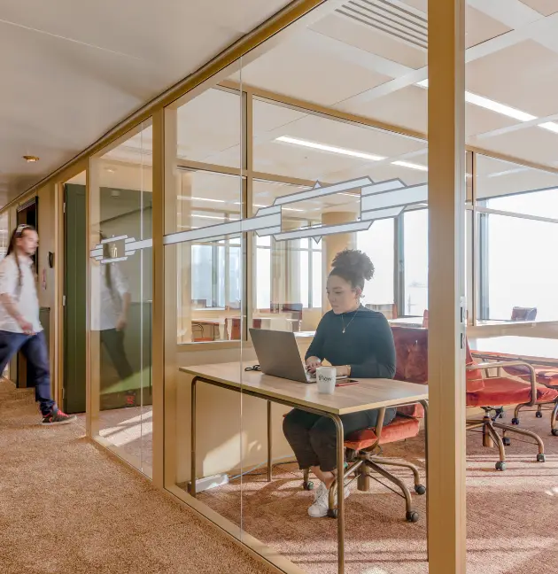 Femme travaillant dans un bureau privatif lumineux avec vue sur le quartier de La Défense