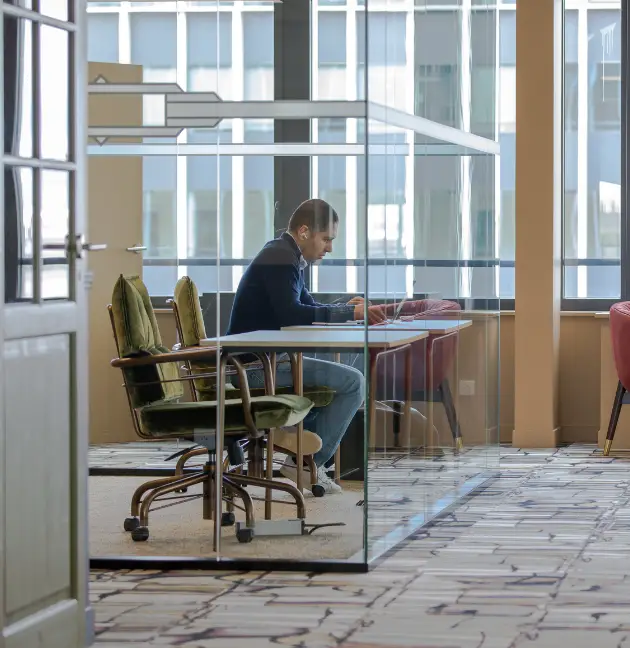 Vue d’un espace de coworking moderne à Courbevoie avec un professionnel concentré dans une cabine vitrée.