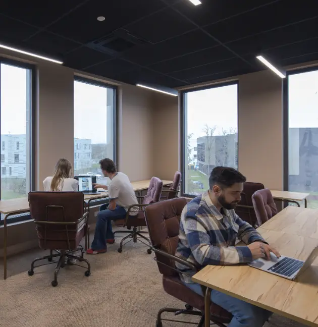 Espace lumineux de coworking Isneauville avec des coworkers concentrés.