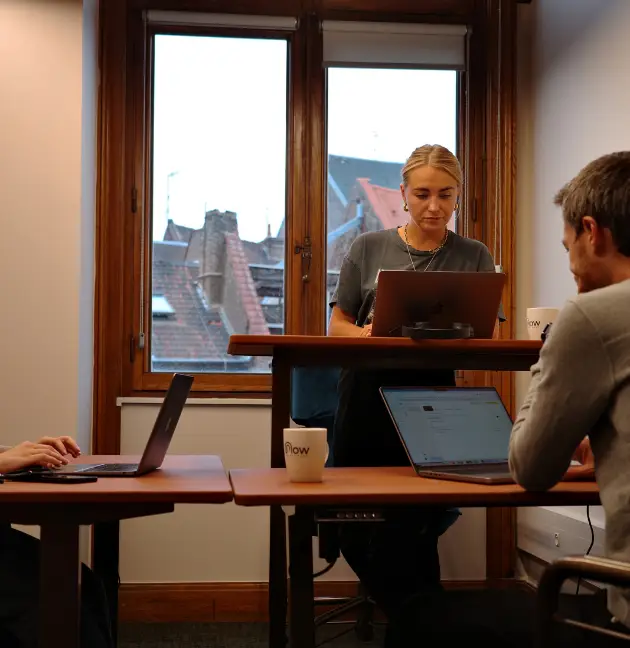 Coworkers travaillant dans une salle avec vue sur Lille, entourés de grandes tables ajustables.