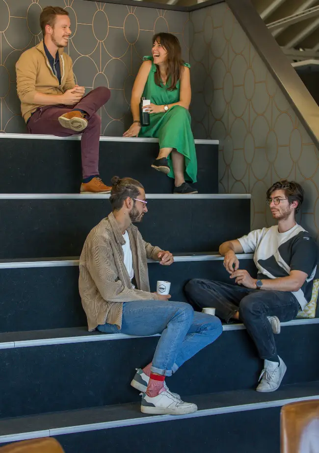 Coworkers en discussion sur des gradins dans l'espace convivial de Now Lyon.