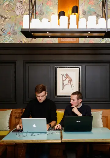 Coworkers collaborant dans une salle lumineuse avec des suspensions modernes à Now Lille.