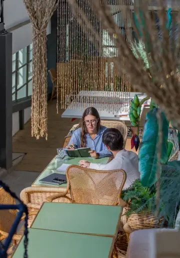 Deux coworkers discutant autour d’une table en bois chez Now coworking Lyon.