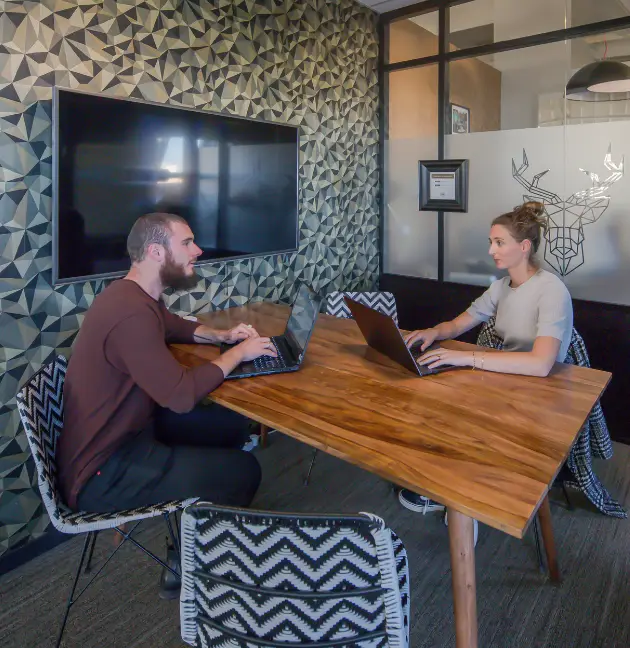 Deux coworkers en réunion dans une salle avec une table en bois chez Now Lyon.